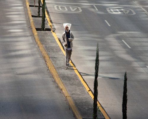 Mujer madura sonriendo mientras camina tranquilamente por una calle arbolada en Ciudad de México