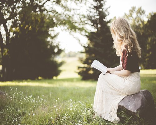 Mujer leyendo un libro sentada con buena postura en un sillón cómodo